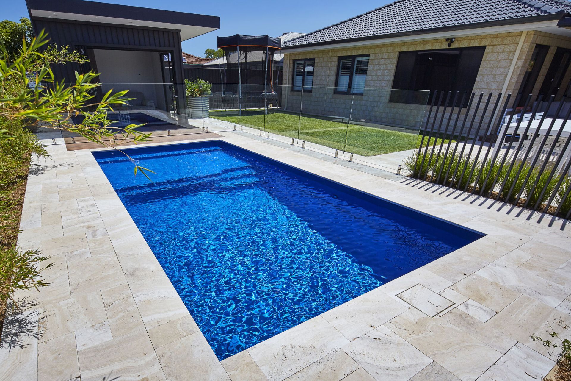 A Large Swimming Pool With A Glass Fence Around It — Gibson Family Pools Pty Ltd In Port Macquarie, NSW