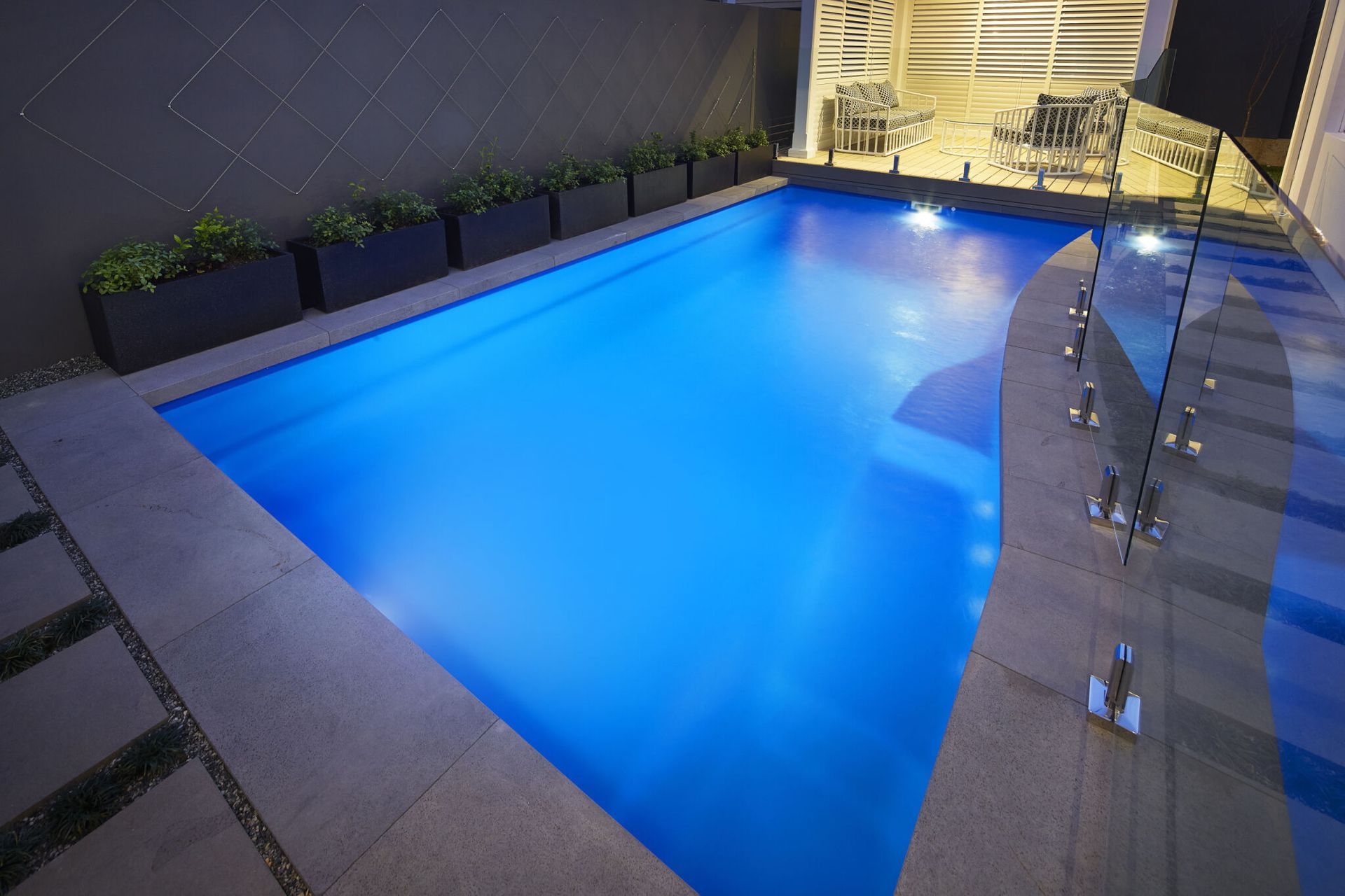A Large Swimming Pool With A Glass Fence Around It — Gibson Family Pools Pty Ltd In Port Macquarie, NSW