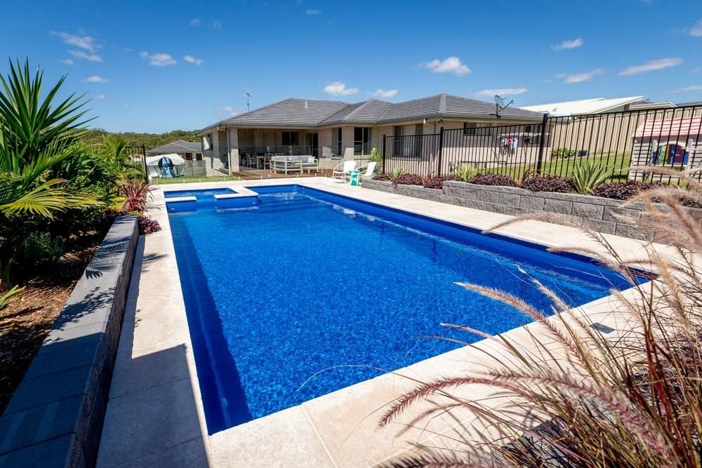 A Large Swimming Pool is in the Backyard of a House — Gibson Family Pools Pty Ltd In Port Macquarie, NSW