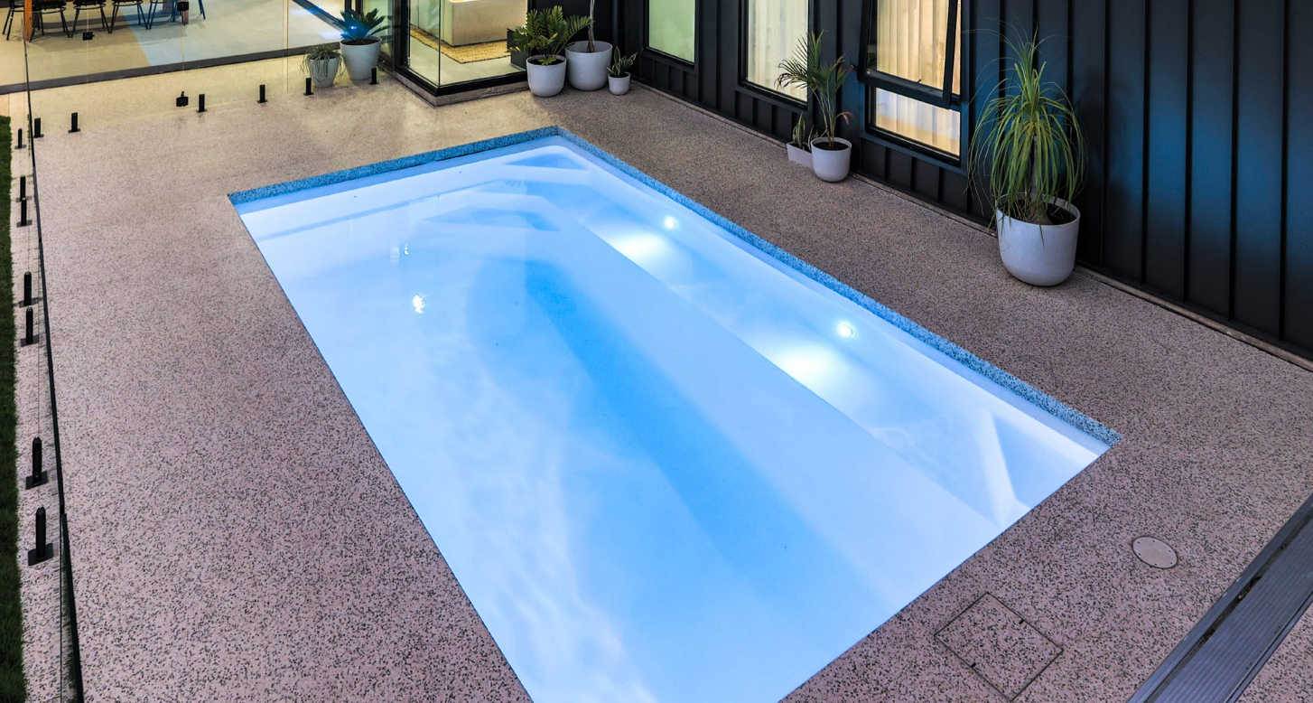 A Large Swimming Pool With A Glass Fence Around It — Gibson Family Pools Pty Ltd In Port Macquarie, NSW