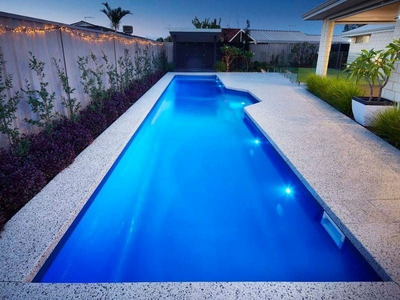A Large Swimming Pool Is Lit Up With Blue Lights — Gibson Family Pools Pty Ltd In Port Macquarie, NSW