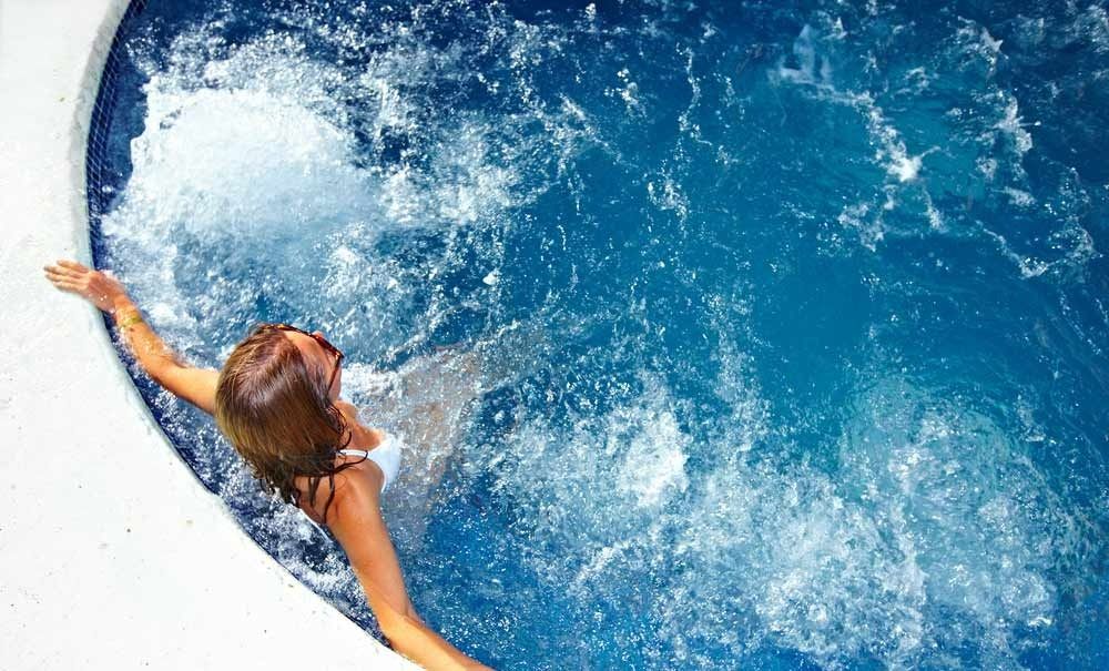 A Woman Is Swimming In A Jacuzzi Pool — Gibson Family Pools Pty Ltd In Port Macquarie, NSW