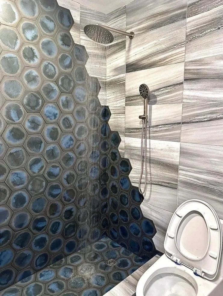 Bathroom with blue bubble-pattern shower wall and an open toilet seat on the right.