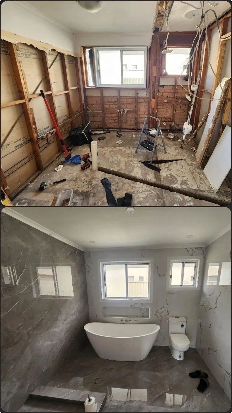 Bathroom renovation: exposed studs above and a finished gray tiled bath below with tub and toilet.