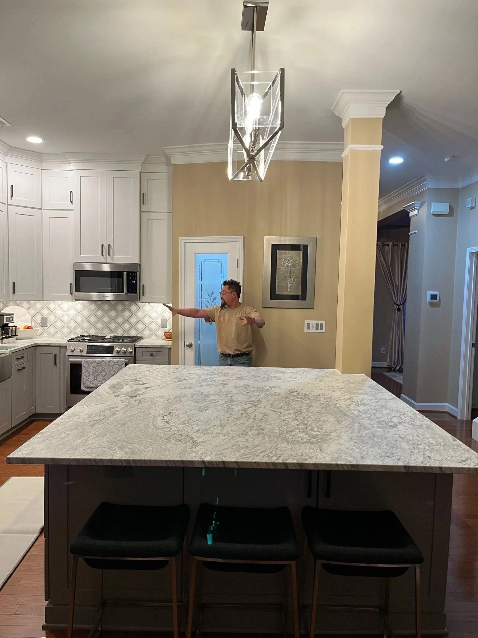 Person standing in a bright kitchen behind a granite island, holding a bowl.