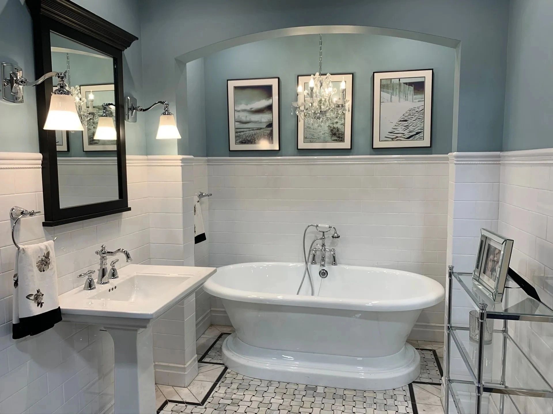 Bright bathroom with clawfoot tub, pedestal sink, mirror, and blue walls with white wainscoting.