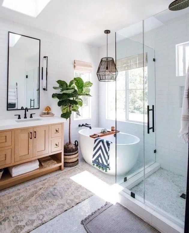 Bright modern bathroom with freestanding tub, glass shower, wood vanity, and potted plant