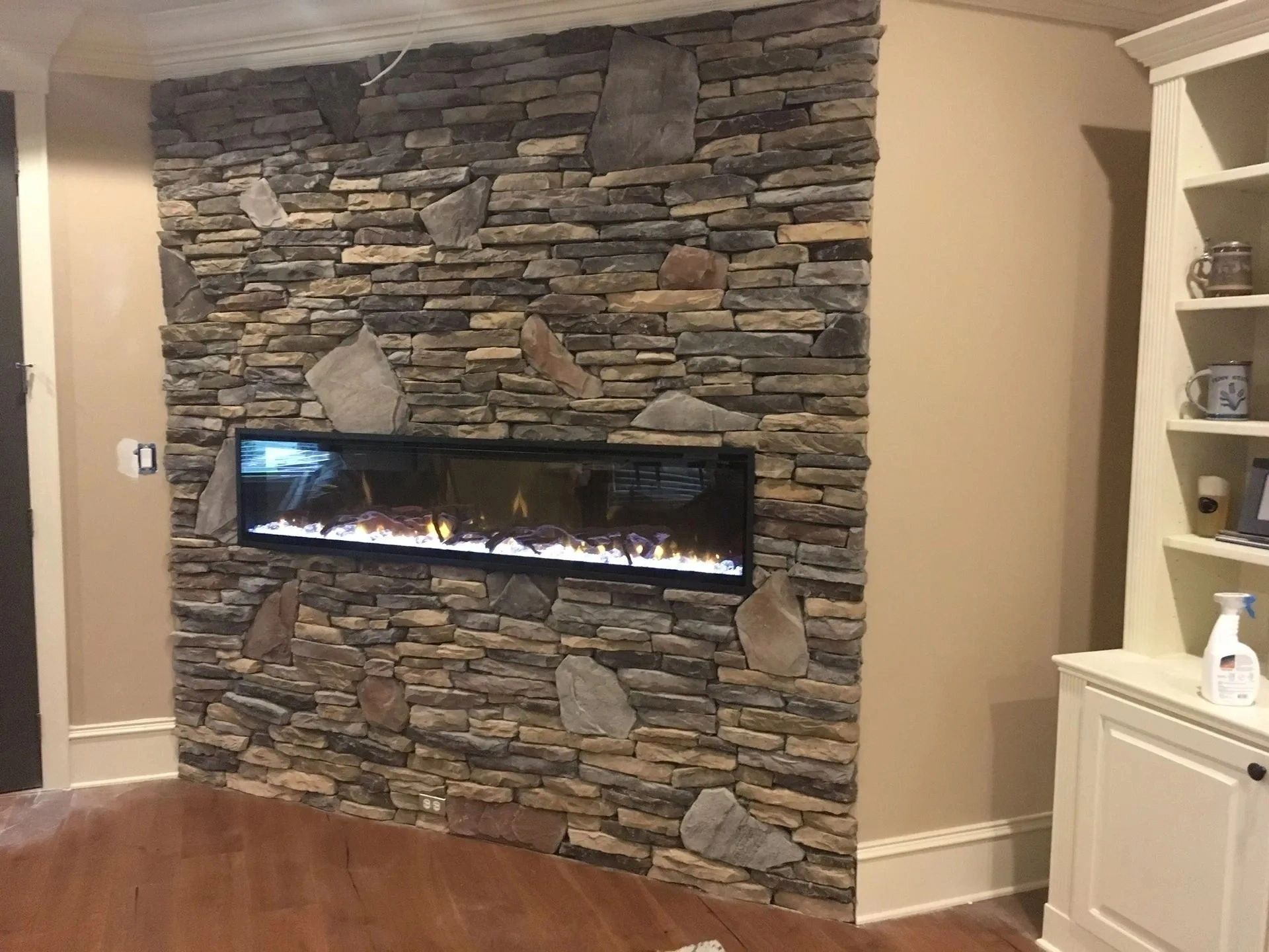 Stone fireplace wall with a modern horizontal gas fireplace in a living room