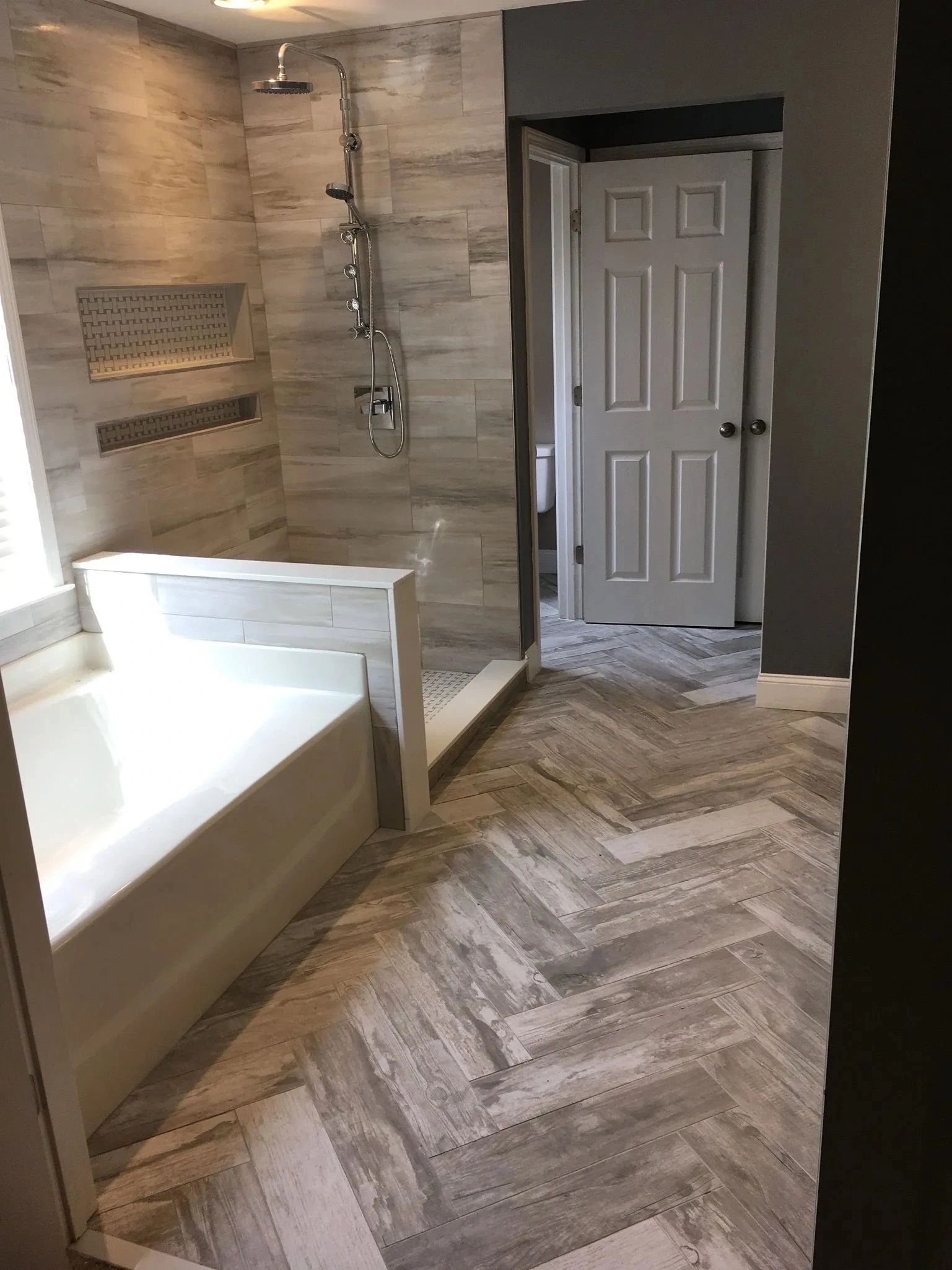 Bathroom with walk-in shower, white tub, and tiled floor in a beige interior