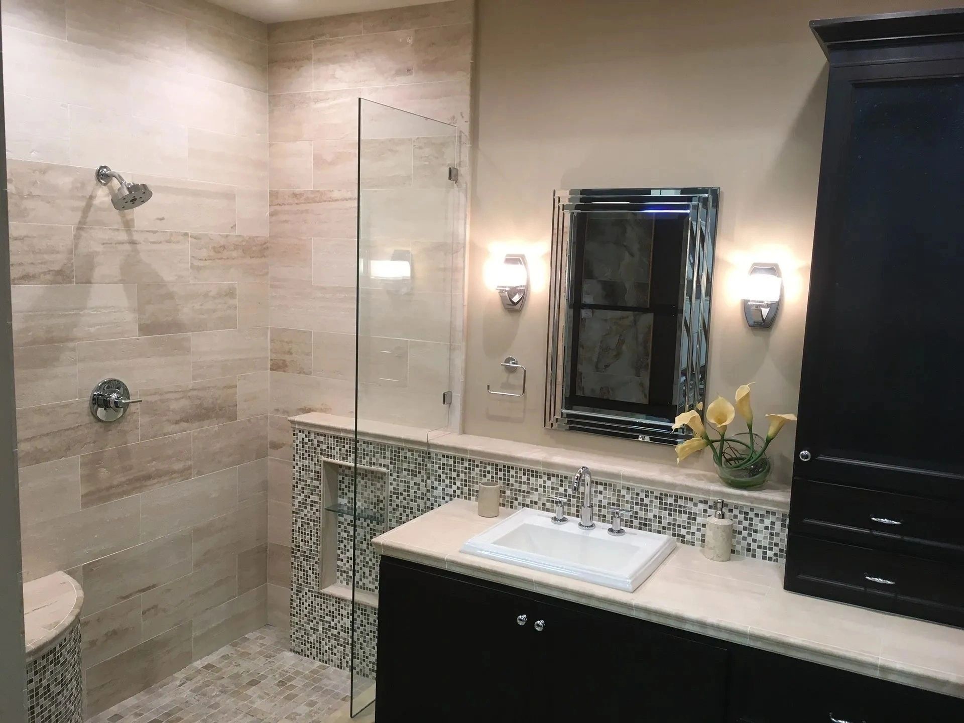 Modern bathroom with tiled shower, decorative mirror, sink, and vanity lighting