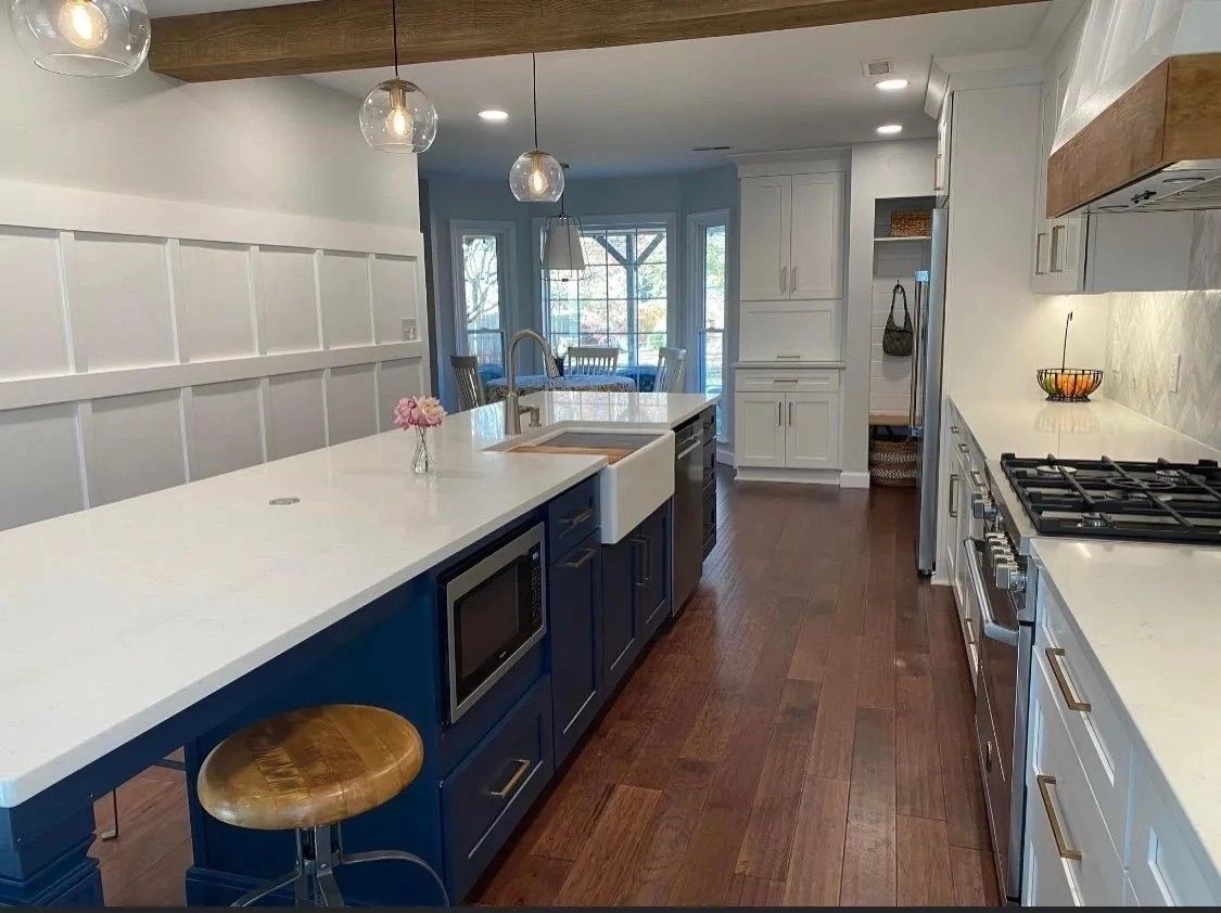 Long, bright galley kitchen with blue lower cabinets, white countertops, and hardwood floors