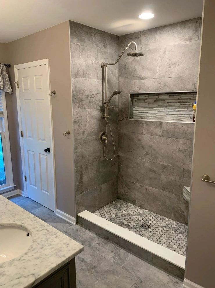 Gray-tiled walk-in shower with glassless entry, rainfall showerhead, and built-in niche in a bathroom
