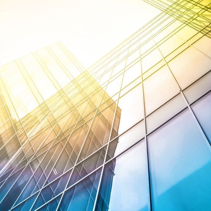Skyscraper with glass windows reflects the sky, bathed in sunlight.