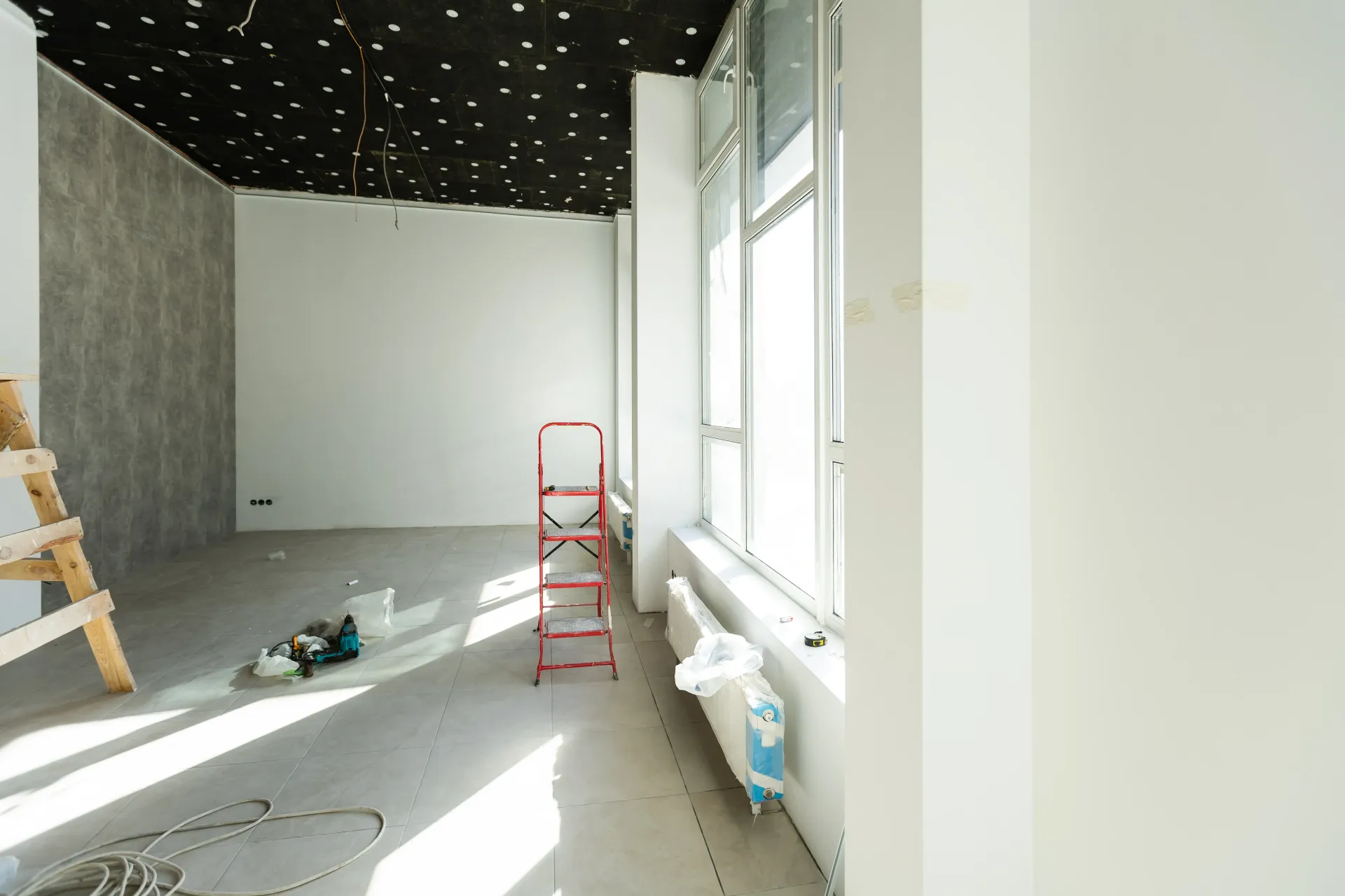 Commercial remodeling services with red ladder, tools, and bright windows on the right