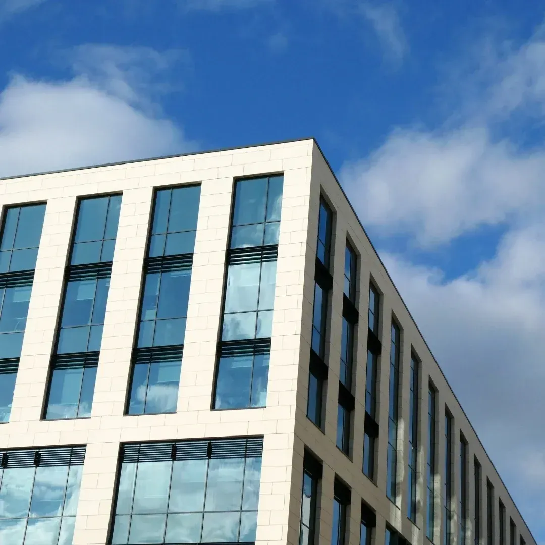 Modern office building with blue windows against a partly cloudy sky Modern office building with blue windows against a partly cloudy sky