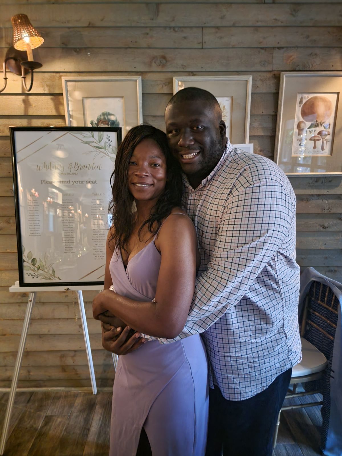 A man and a woman are posing for a picture in front of a sign.