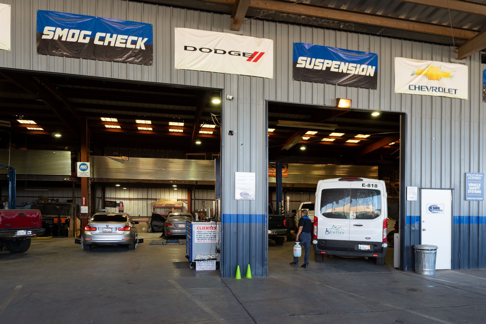 Exterior of auto repair shop with multiple bays. Smog check and other banners hang above the bays.
