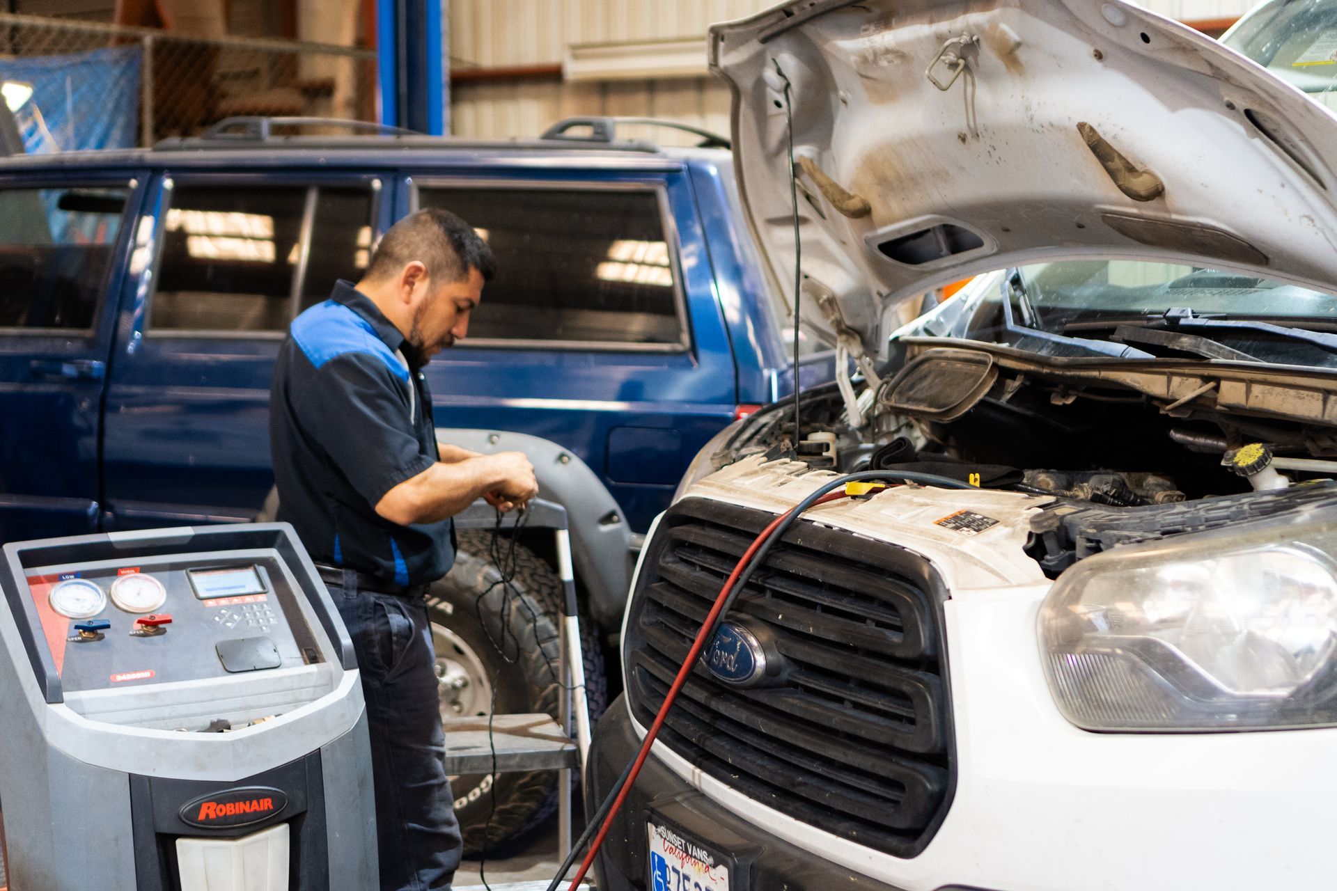 Mechanic working on a car in a shop, using a diagnostic machine.
