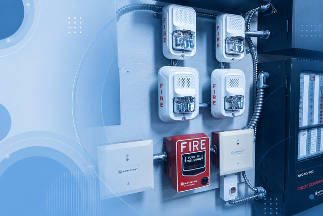 Panel eléctrico con contadores, caja de alarma contra incendios e interruptores montados en una pared azul.
