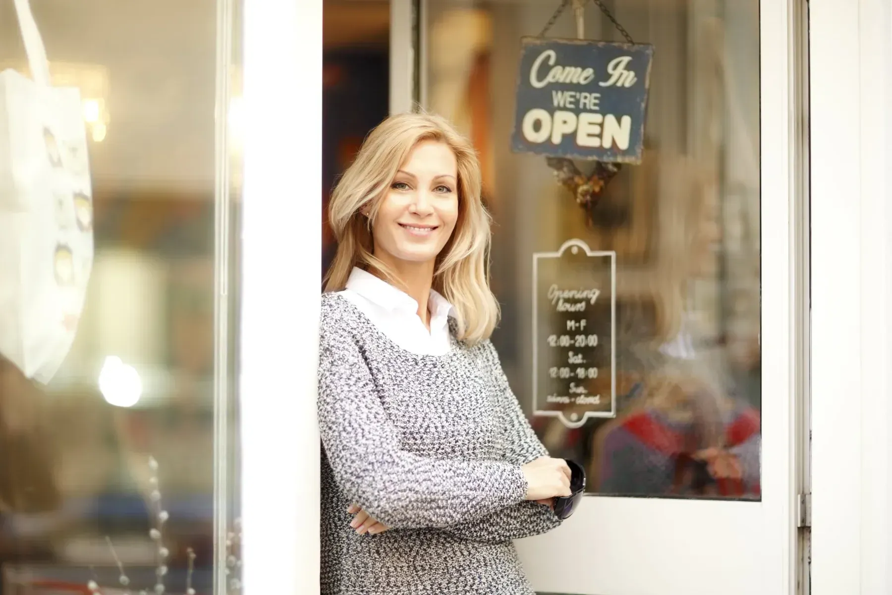 A Woman is Standing in Front of a Store Door With a Sign — Orana Glass In Dubbo, NSW