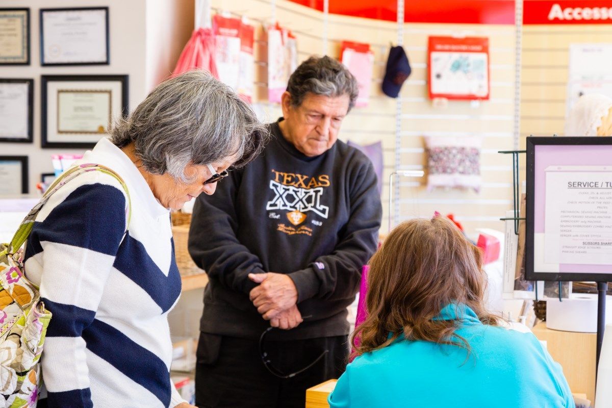 Three people talking at a service counter in a bright office waiting area