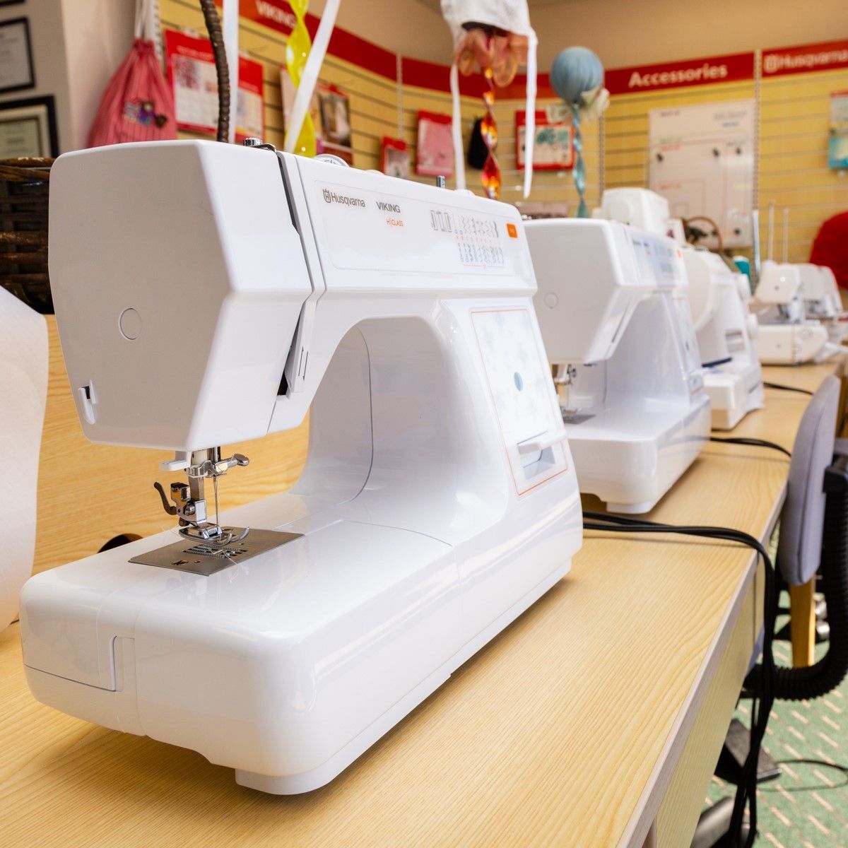 Row of white sewing machines on a store display table in a fabric or sewing shop