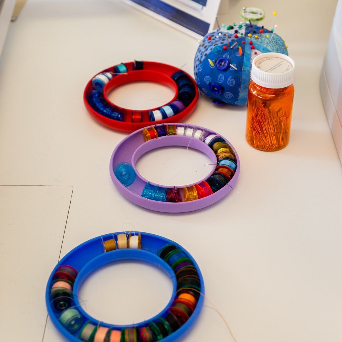 Colorful bracelet-like rings on a white surface beside a blue beaded bag and orange jar