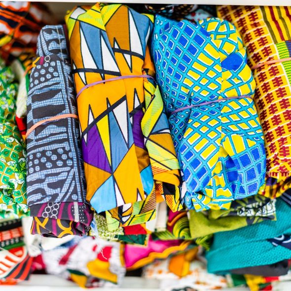 Colorful folded wax-print fabrics stacked in a market display