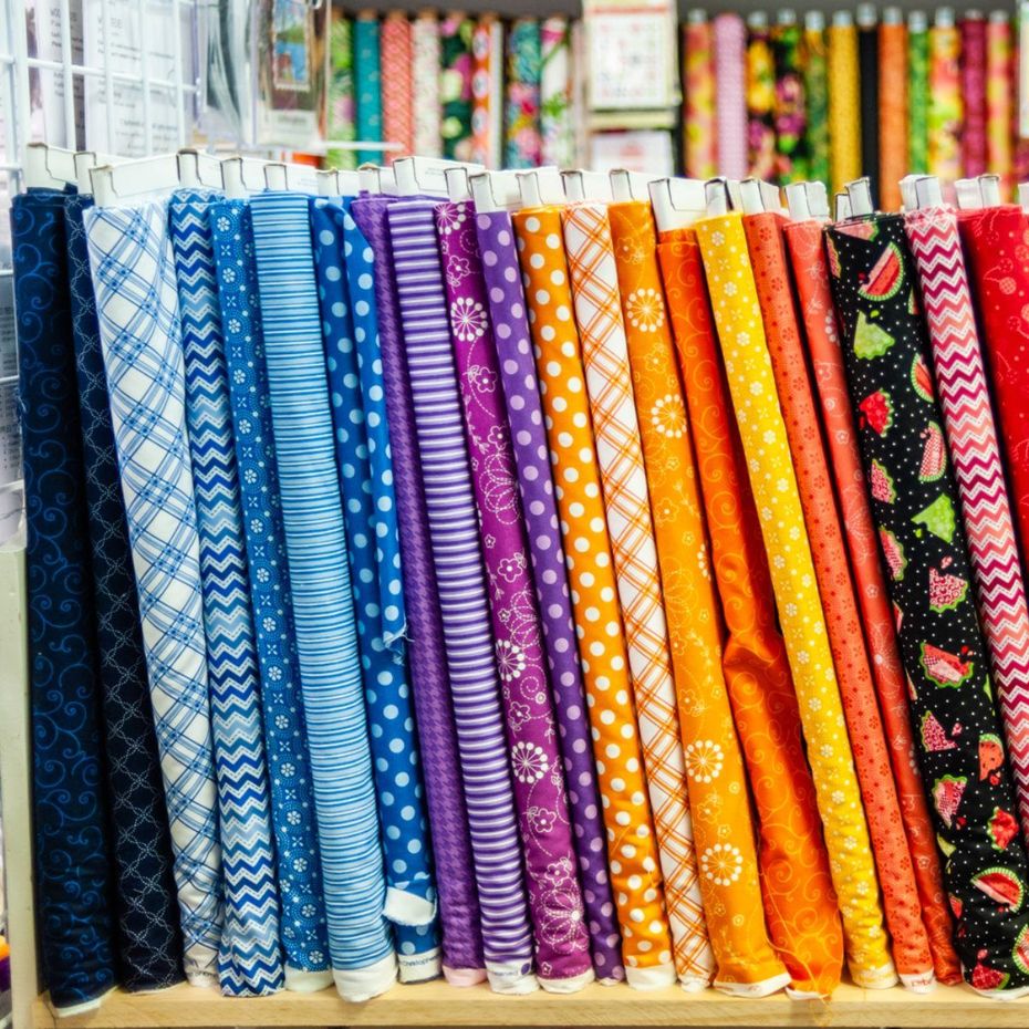 Colorful rolled fabrics with blue, purple, orange, and pink patterns on display in a shop