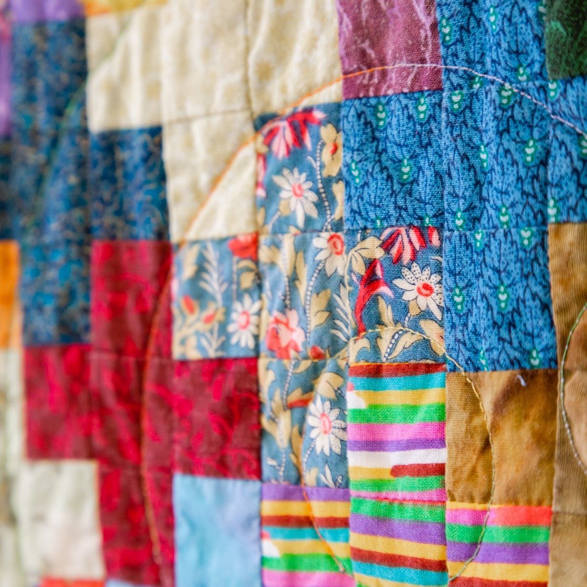 Colorful patchwork quilt with floral, striped, and textured fabric squares