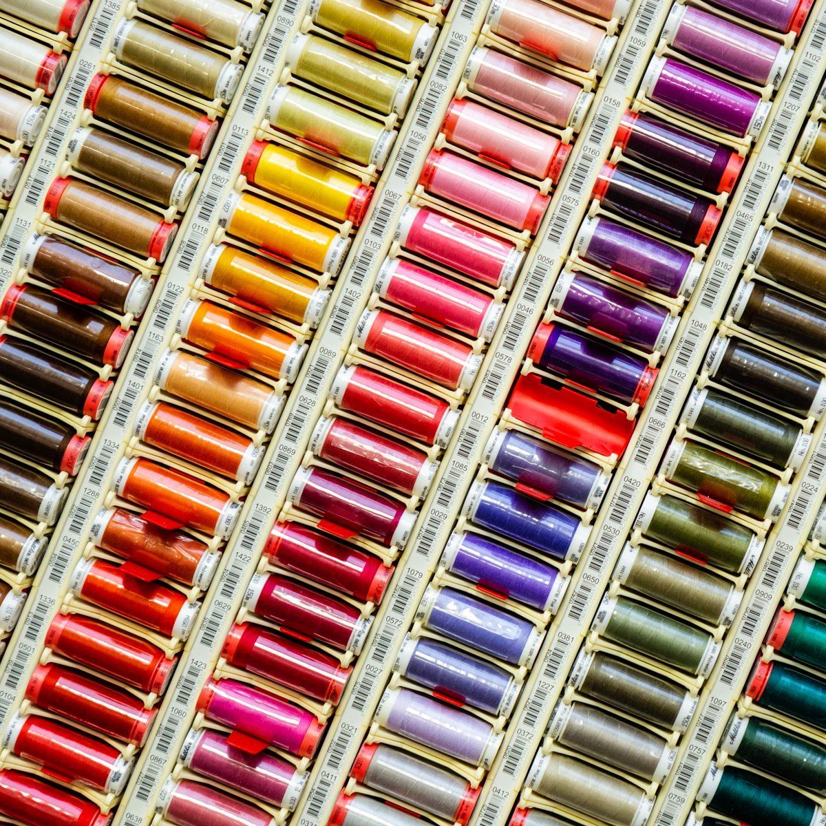 Rows of colorful thread spools arranged diagonally in a neat, patterned display.