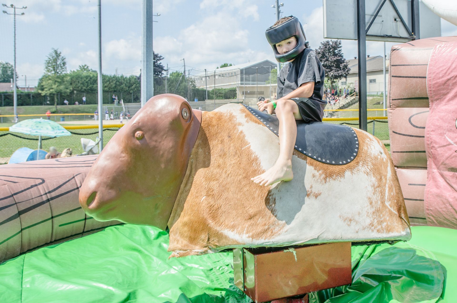 A young boy wearing a helmet is riding a mechanical bull.