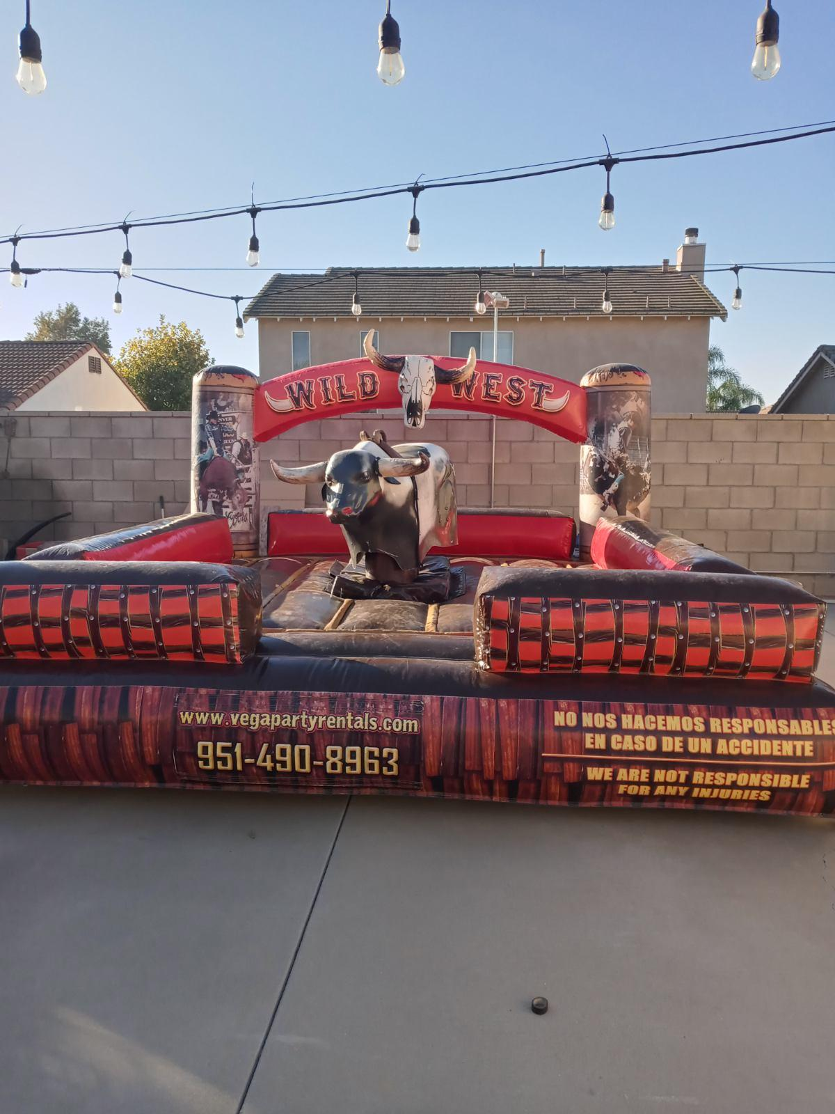 A man is riding an inflatable bull in a backyard.