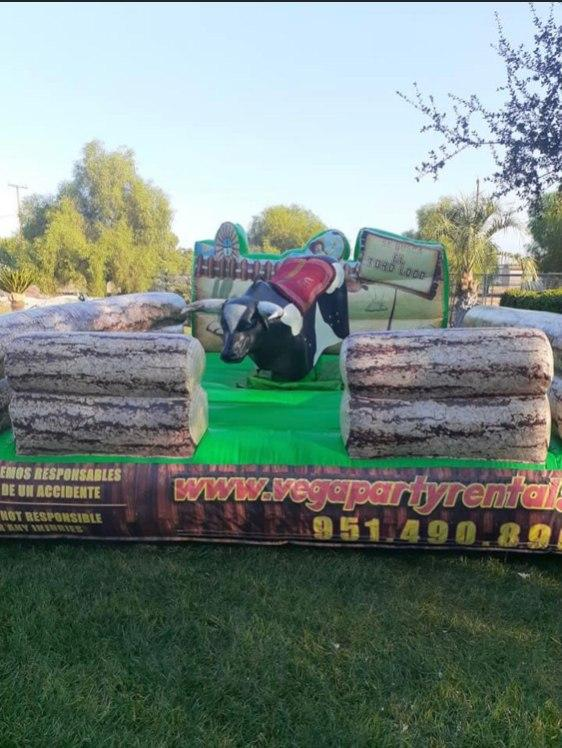 A large inflatable bull is sitting on top of a grass covered field.
