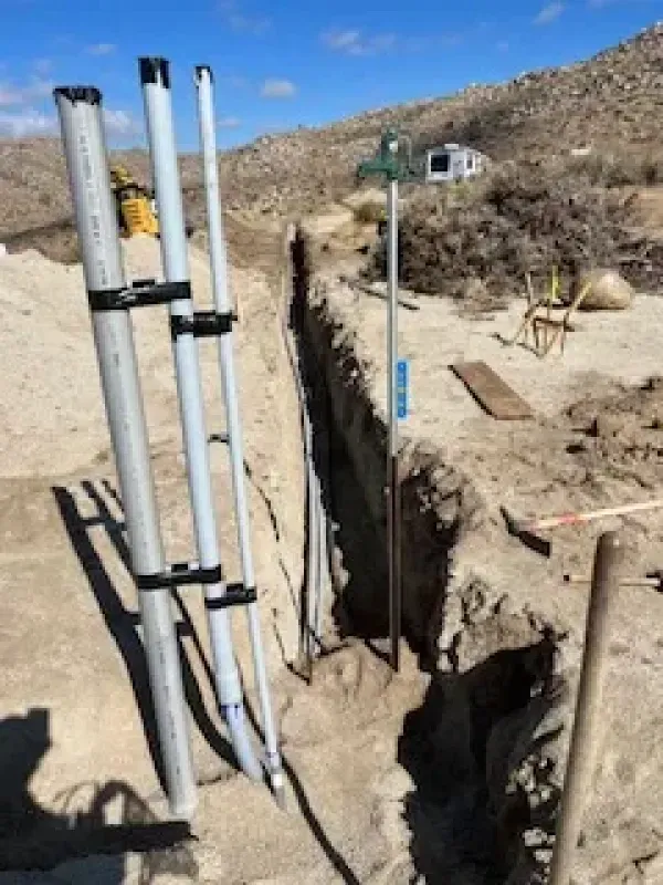 A bunch of pipes are sitting on top of a pile of dirt.