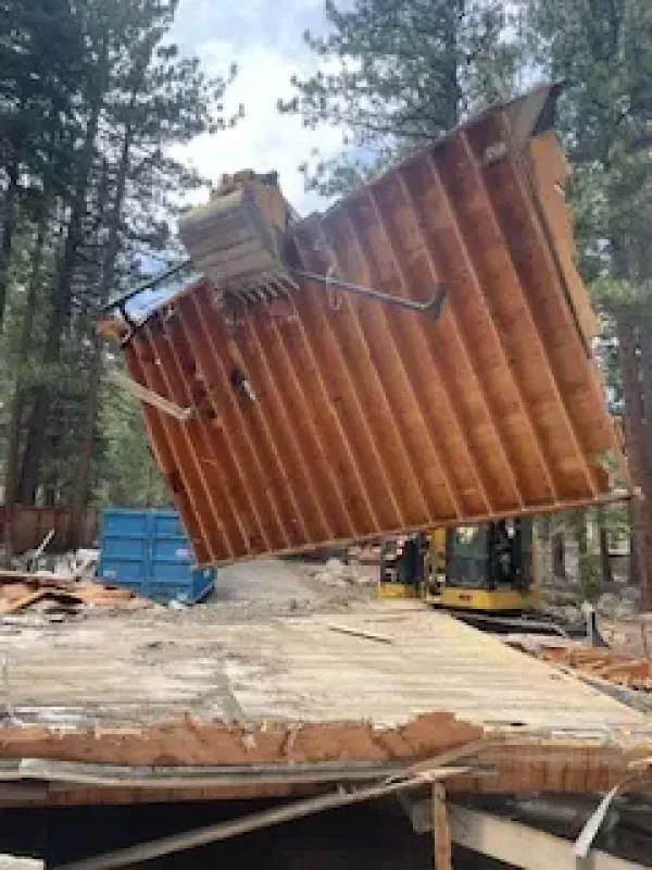 A large wooden structure is being demolished by a bulldozer.