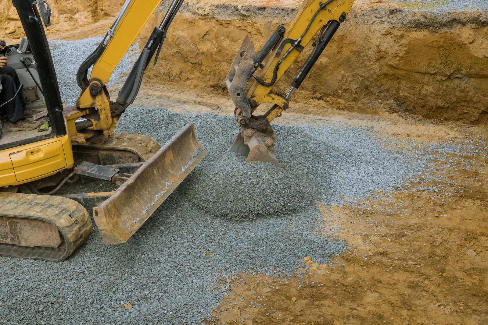 A yellow excavator is digging a hole in the ground.