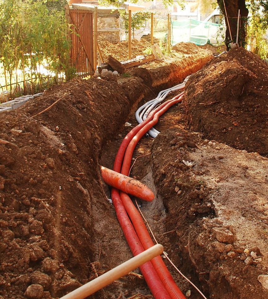 A man is holding a yellow tool in front of a row of pipes.
