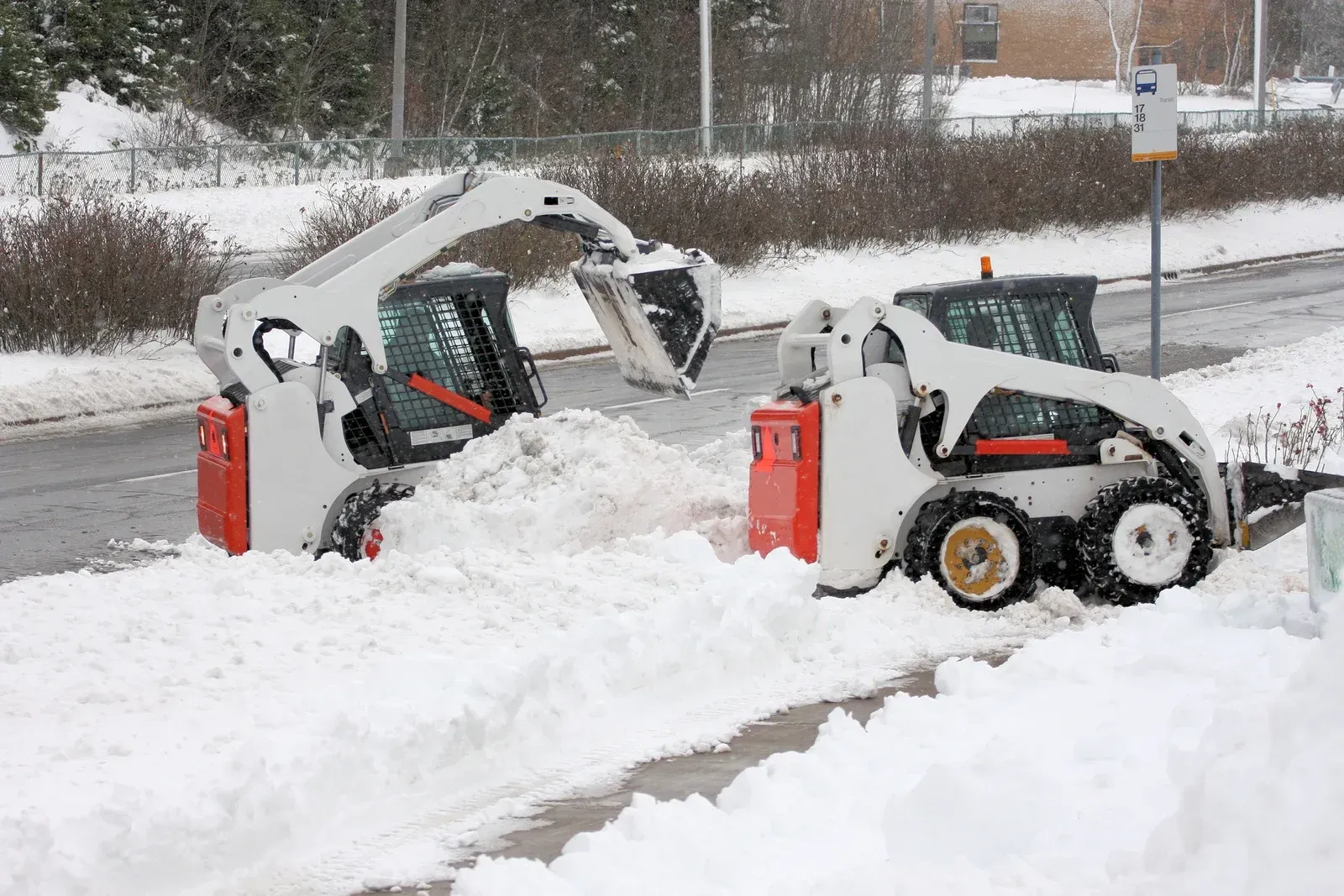 Two snow plows are clearing snow from the side of the road.