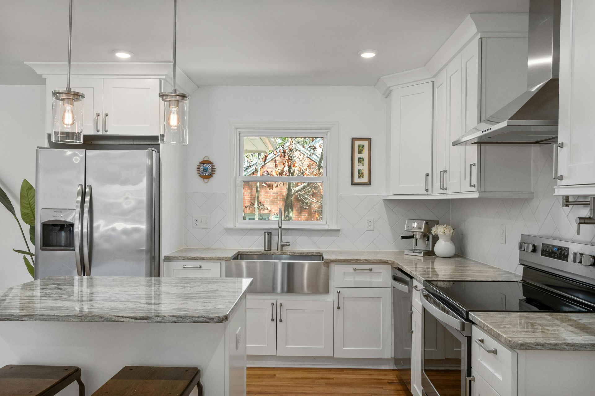 A kitchen with white cabinets , stainless steel appliances , granite counter tops and a sink.