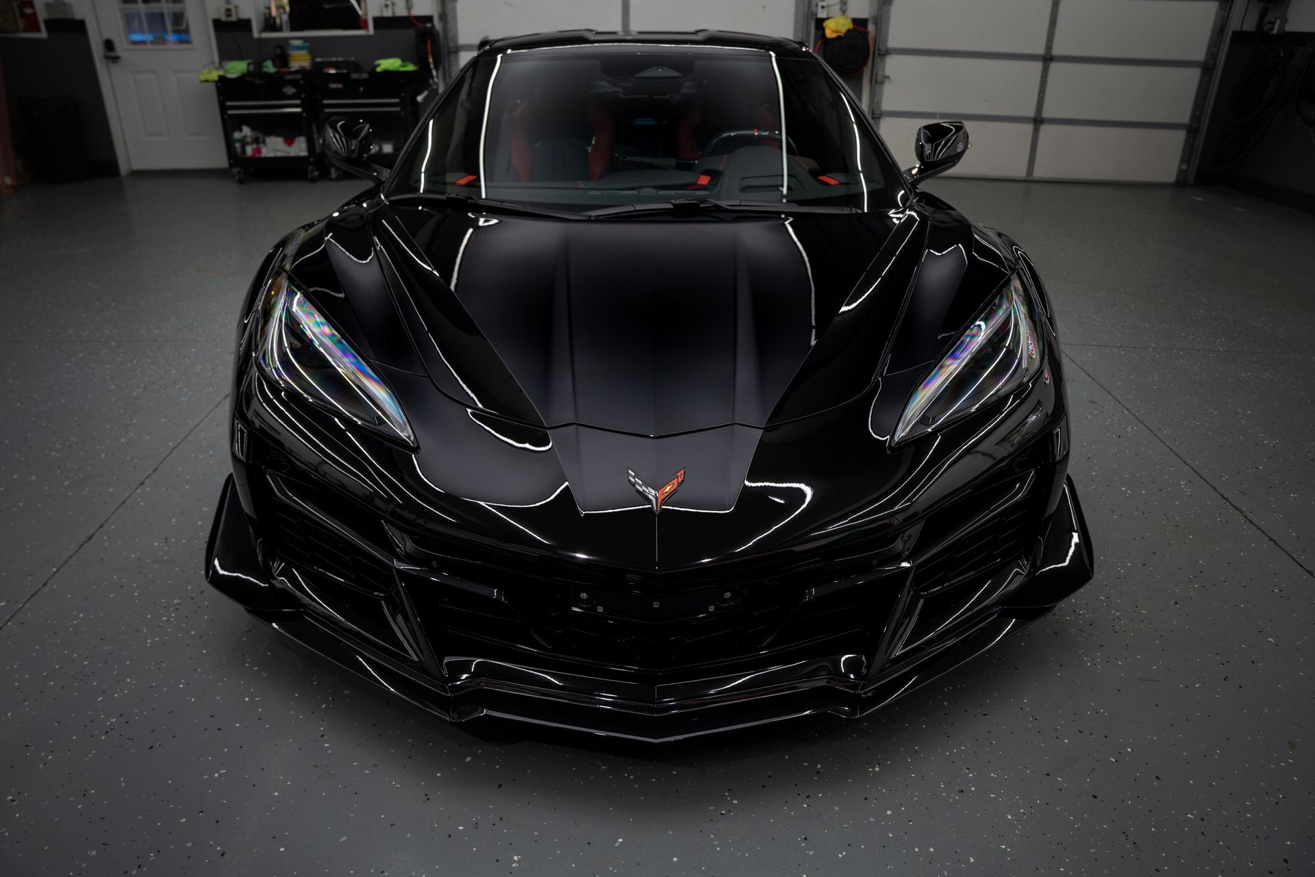 Black Volvo SUV parked in a garage, next to a yellow sports car.