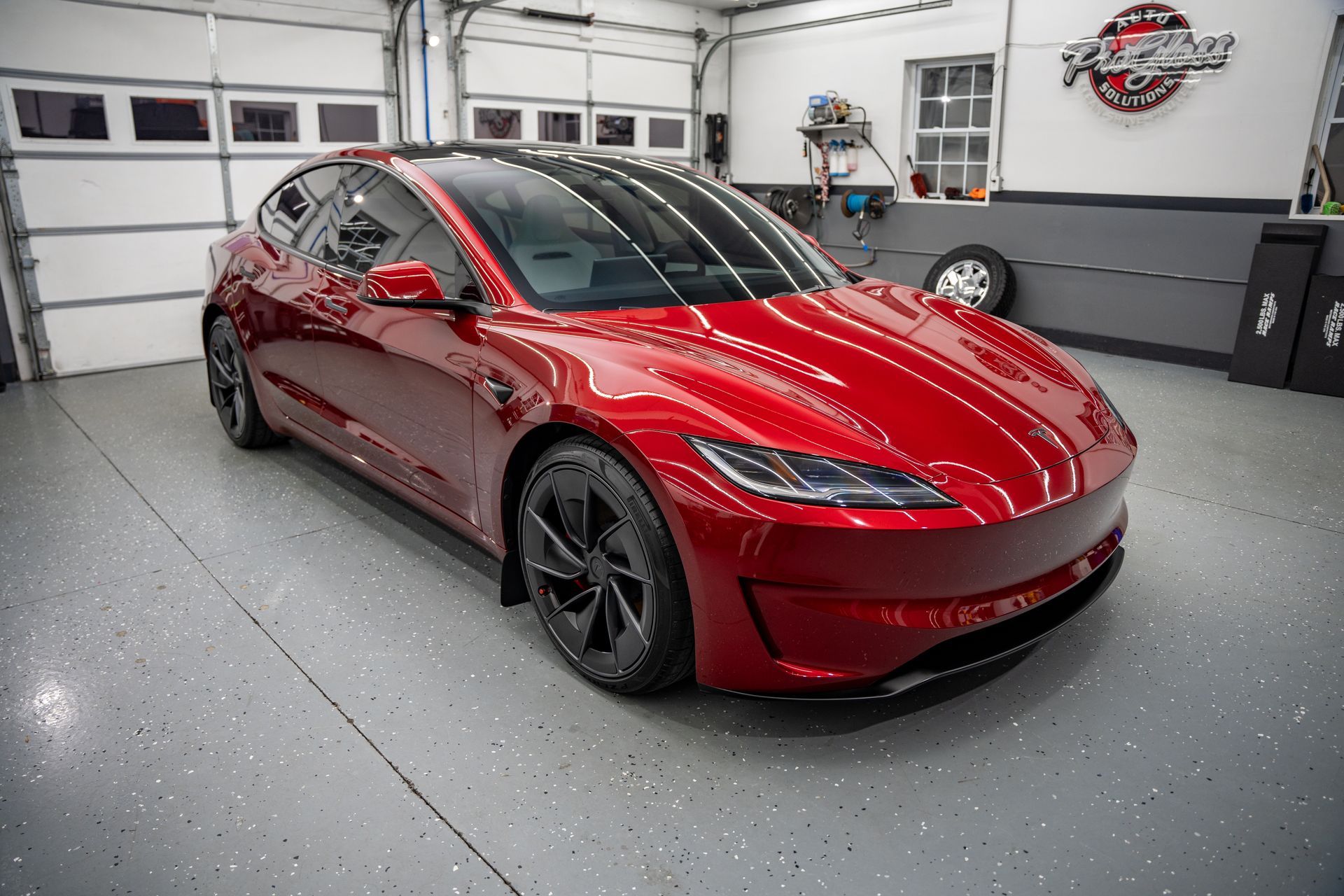 Red BMW M4 coupe in a garage with black wheels.