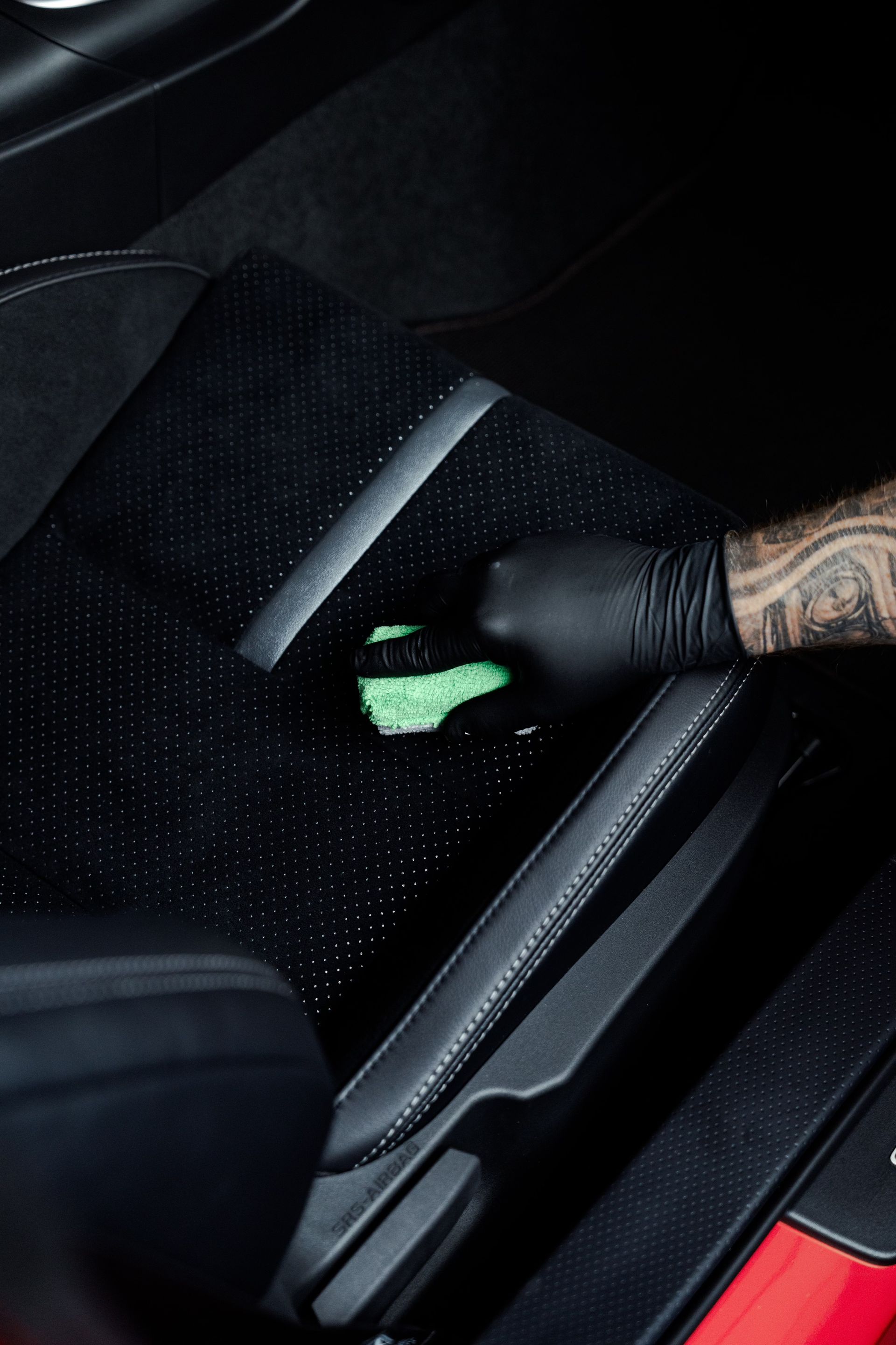 Man with a red beard sprays a surface, possibly applying a film in a shop.