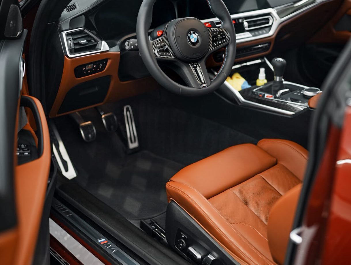 Brown leather interior of a BMW, including steering wheel, seats, and dashboard.