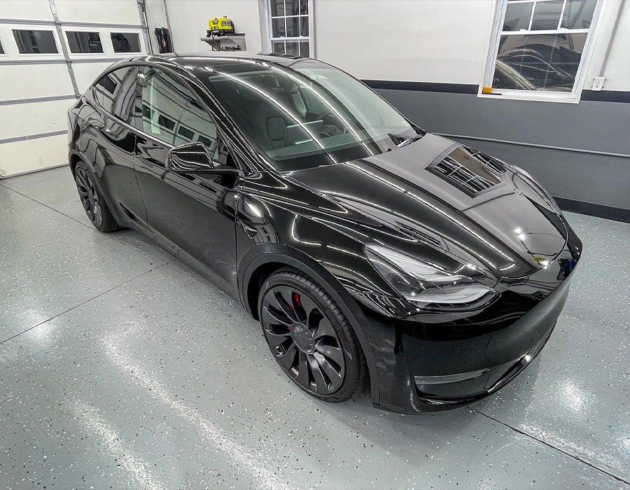 Black Tesla car in a garage with a glossy finish.