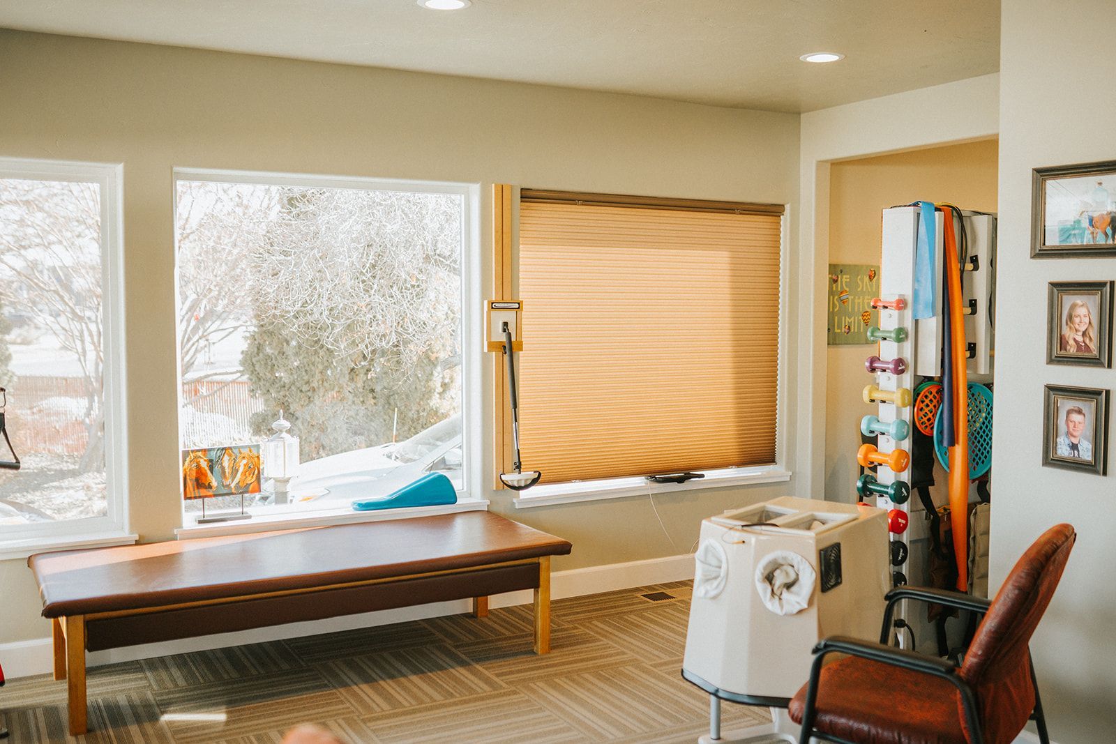 A living room with a table , chair , and windows.