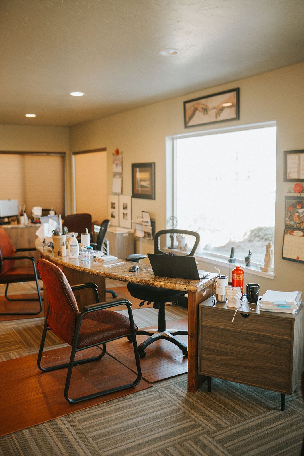 A room with a desk , chairs , and a laptop on it.