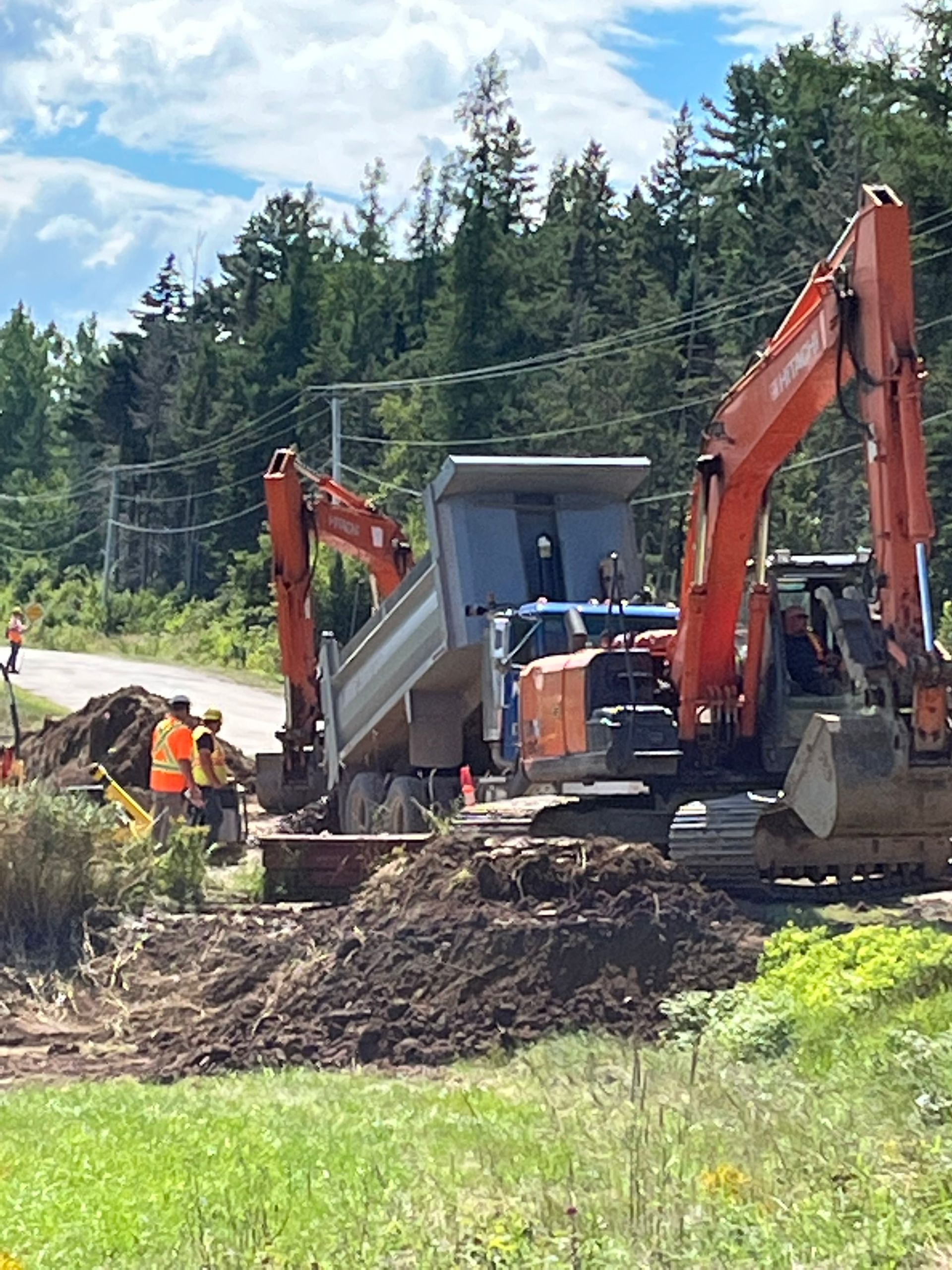 A dump truck is being loaded with dirt by an excavator.