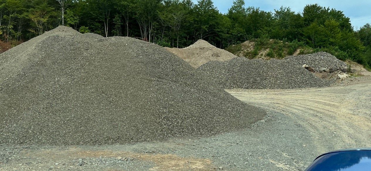 A pile of gravel is sitting in the middle of a dirt road.