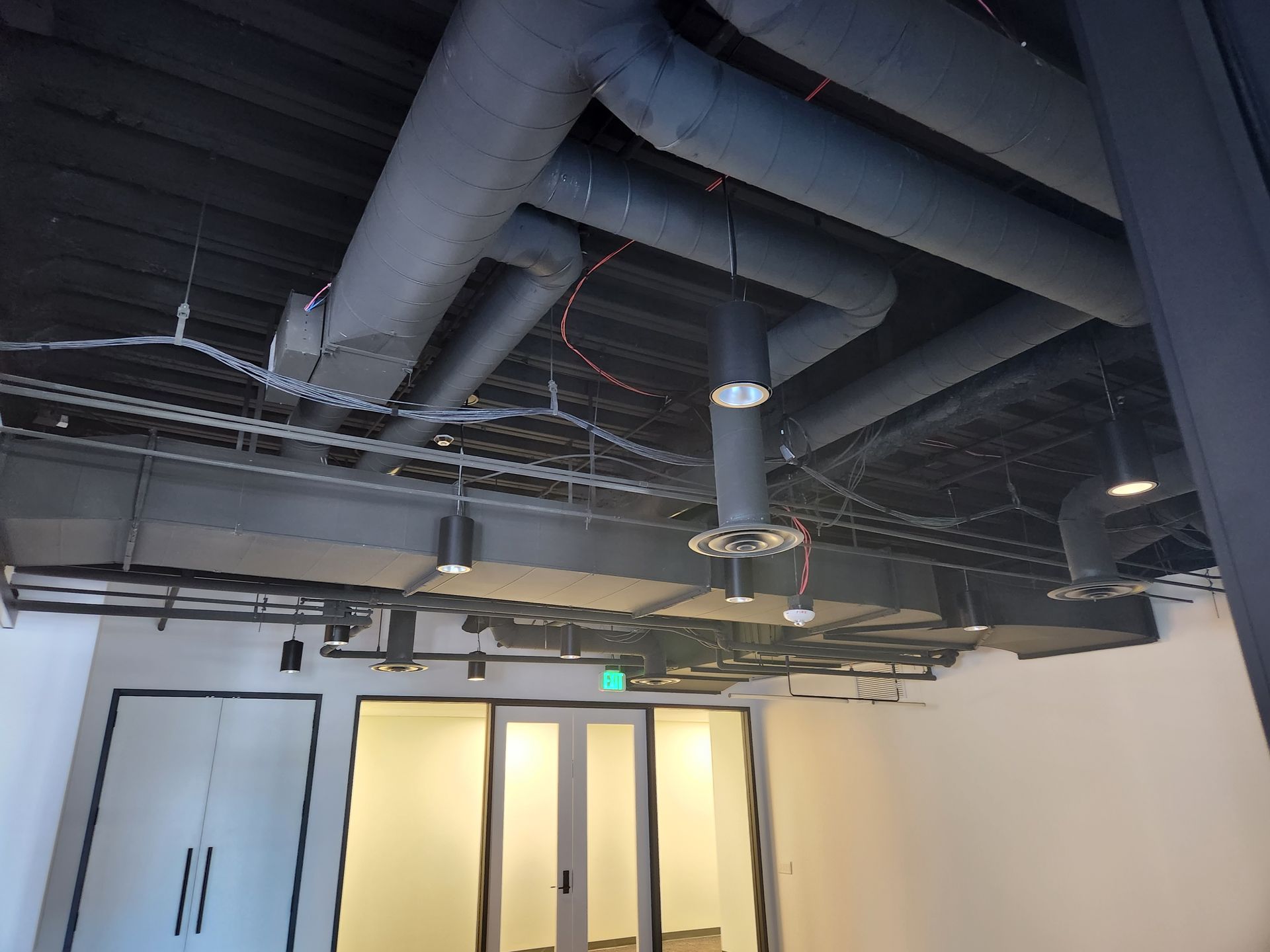 An air conditioner unit sits on a concrete pad next to a beige building. The ground is covered with mulch.